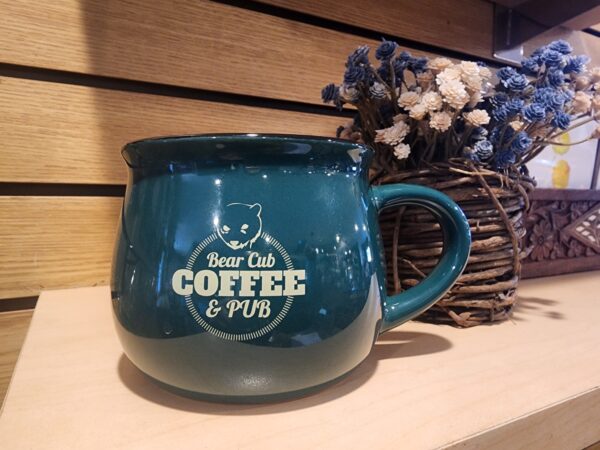 Bear Cub Coffee and Pub coffee mug kept on a wooden shelf.